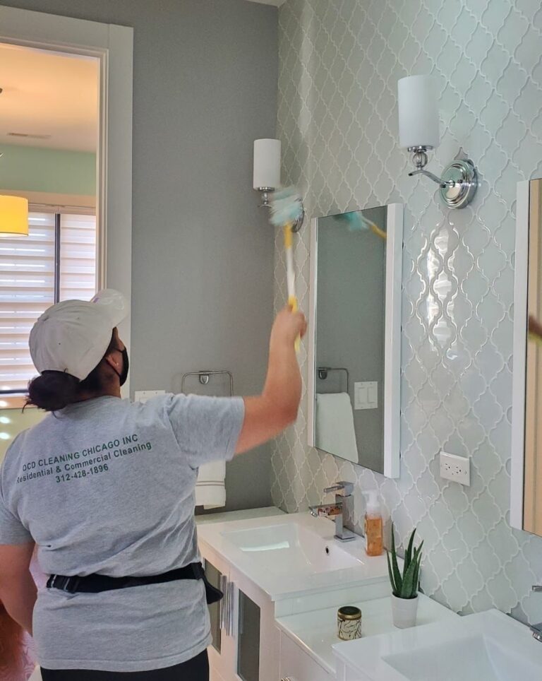 OCD Cleaning employee dusting off bathroom sconces, making sure the entire bathroom has been thoroughly cleaned from top to bottom. Apartment cleaning in Avondale